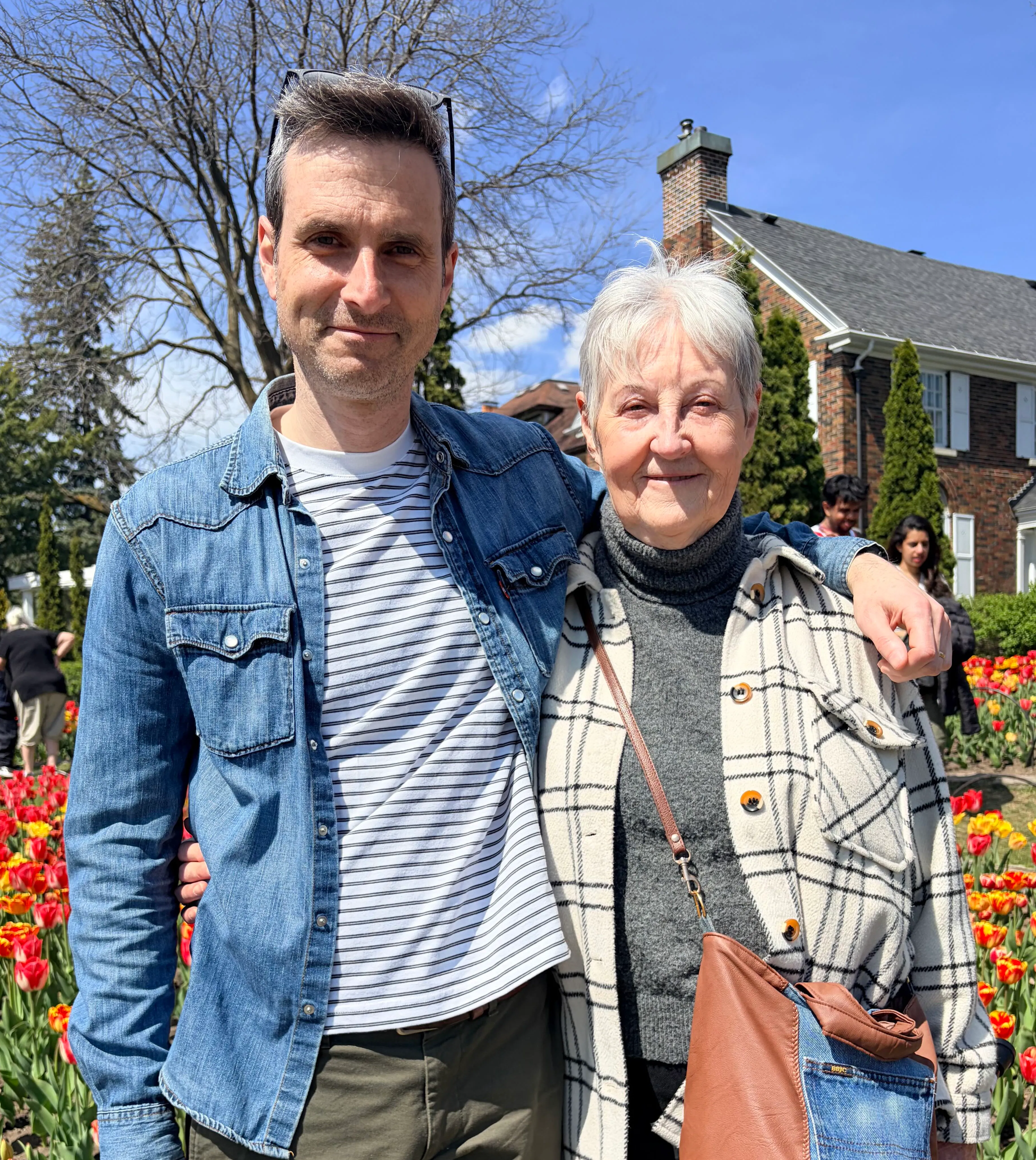 Geoff, owner of Bits & Bolts, smiling with an older woman in front of tulip beds